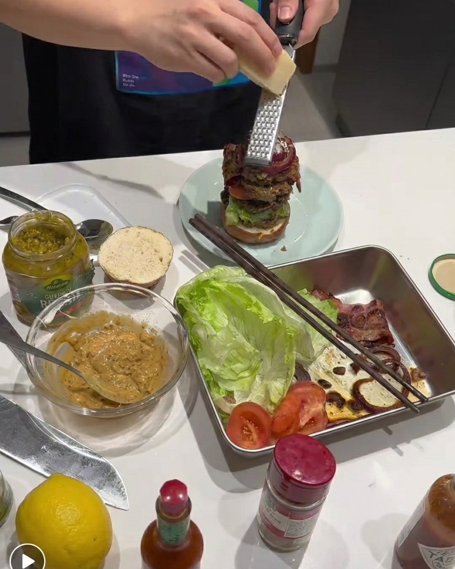 Queso Parmesano fresco rallándose sobre la hamburguesa armada.