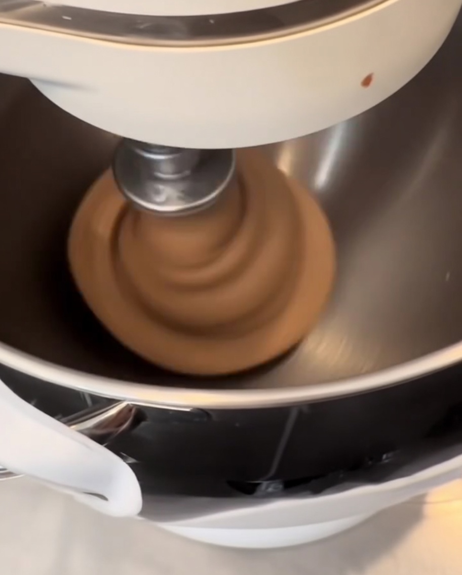 Masa oscura infusionada con cacao siendo formada en bolas suaves y redondas sobre una alfombrilla de silicona.