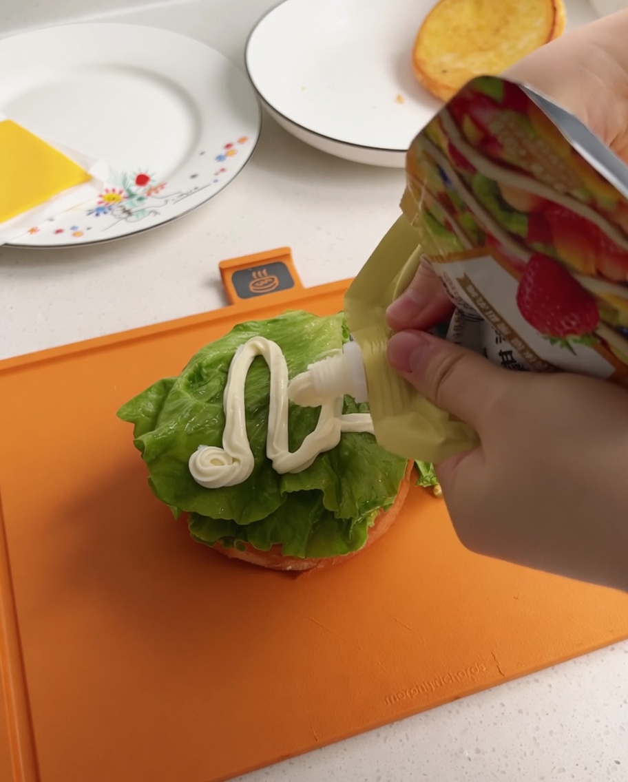 Aderezo blanco para ensalada siendo exprimido desde una bolsa sobre una hoja de lechuga.