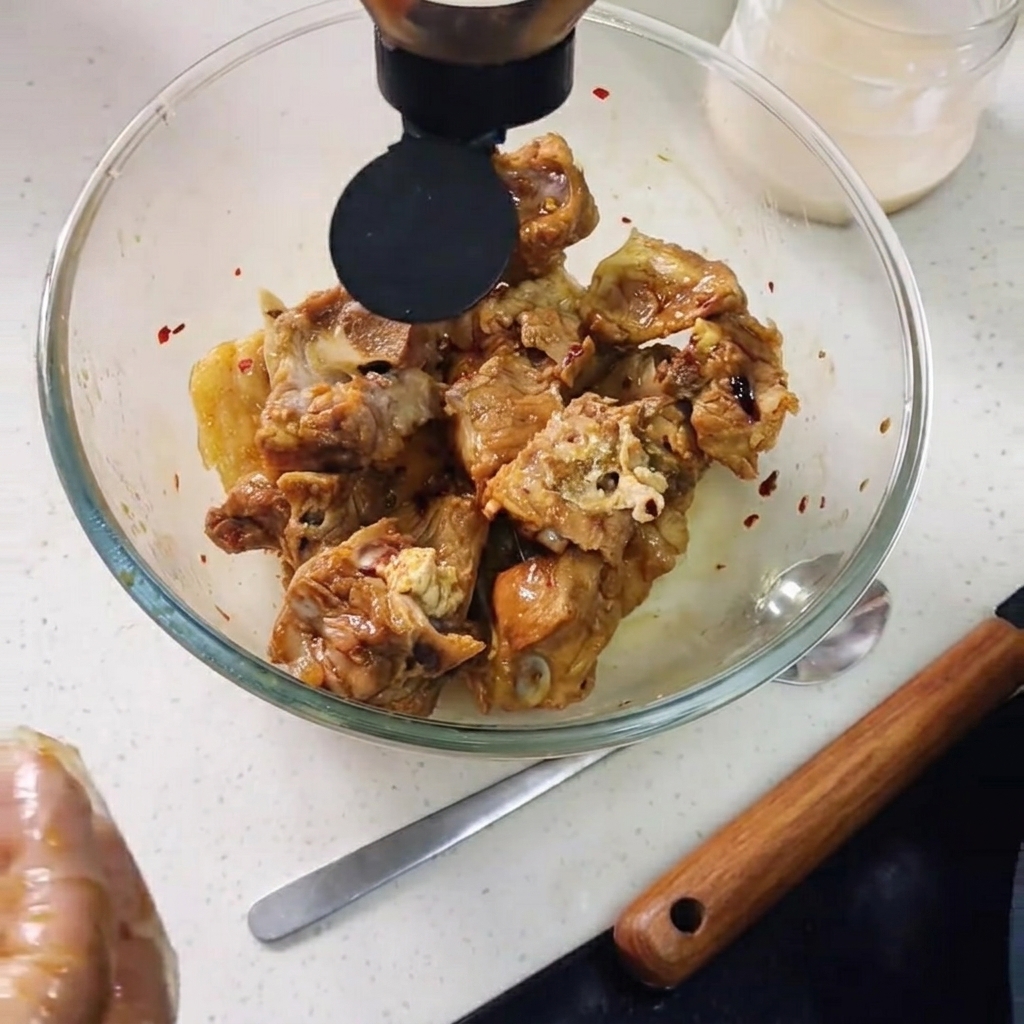 Salsa de ostra siendo vertida en el bol sobre las costillas de cerdo, con rodajas de limón añadidas.