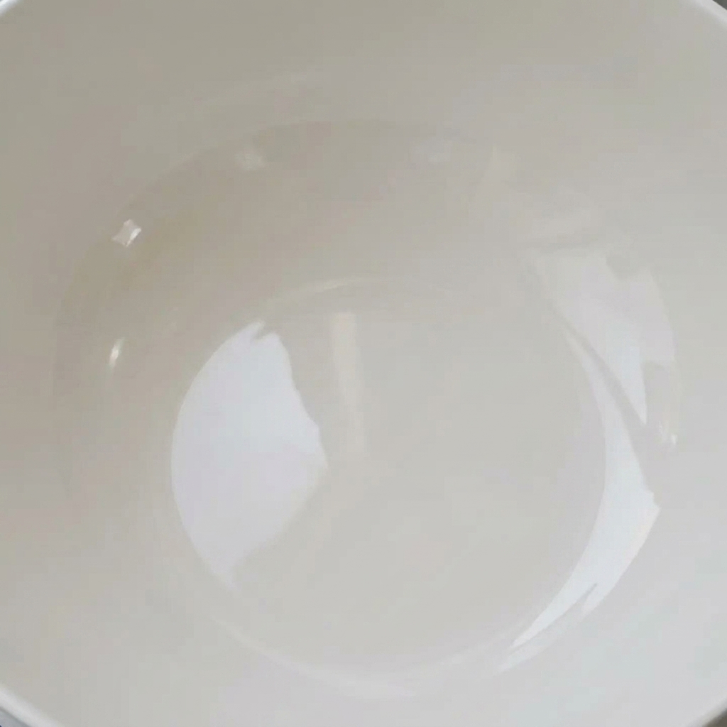 Almejas frescas remojando en un tazón blanco lleno de agua clara, listas para ser purgadas.