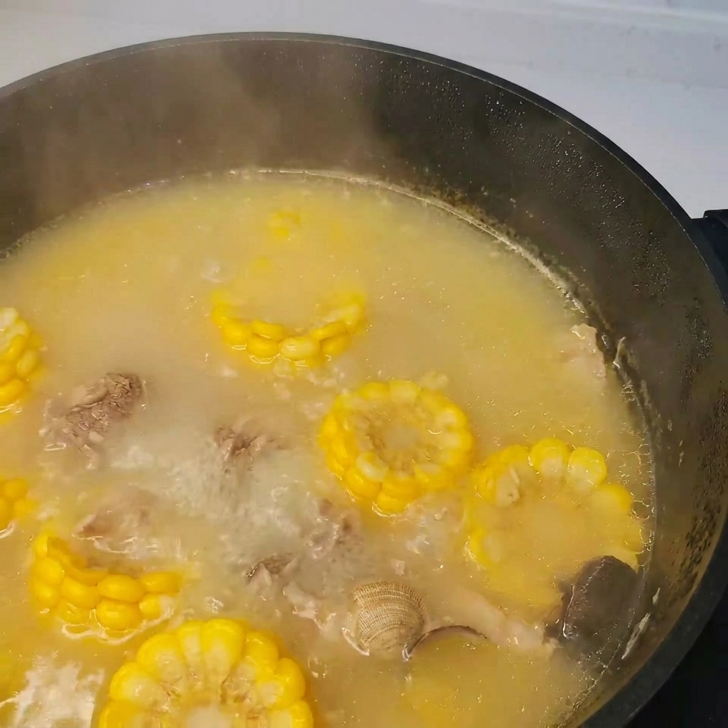 Algas siendo añadidas a la olla de sopa hirviendo de cerdo, almejas y verduras.