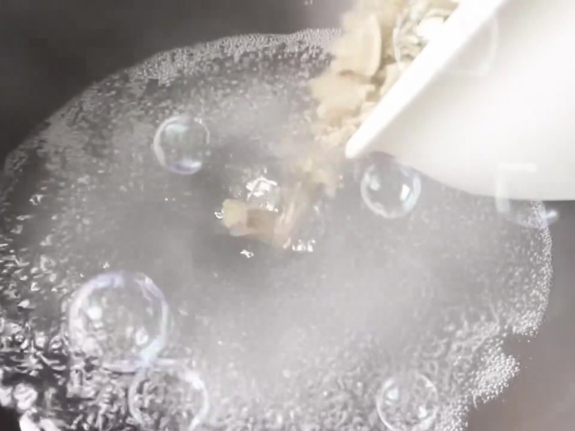 Almejas vertidas en una olla de agua hirviendo con aromáticos.