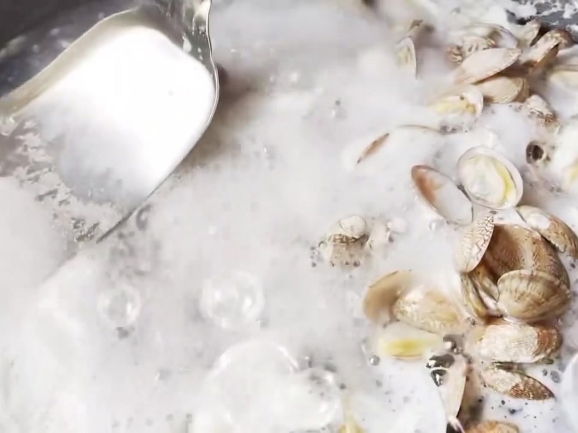 Una espumadera de metal retirando la espuma de la superficie del agua hirviendo.