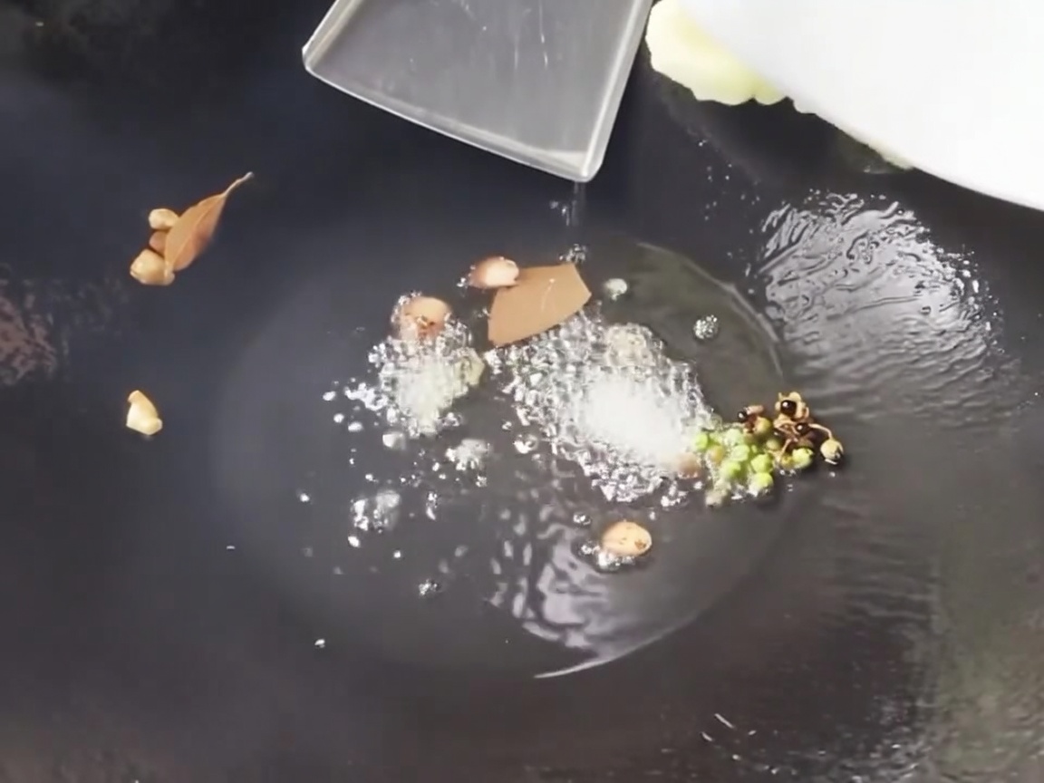 Brotes de bambú recién cortados y segmentos de maíz siendo salteados en un wok caliente con aromáticos.