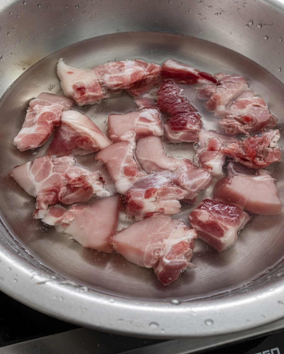 Trozos de costilla de cerdo hirviendo en agua para eliminar impurezas.