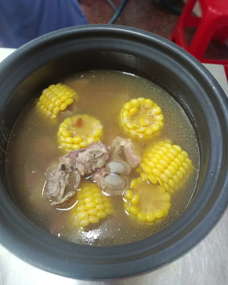 Una olla a presión abierta de forma segura revelando un caldo claro caliente con tiernas costillas de cerdo y maíz amarillo brillante.