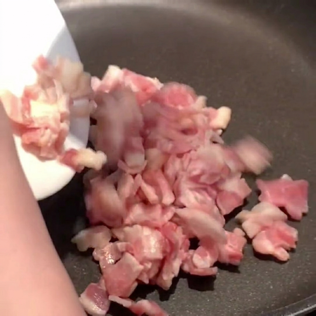 Trozos de tocino chisporroteando en una sartén caliente, soltando su grasa dorada.