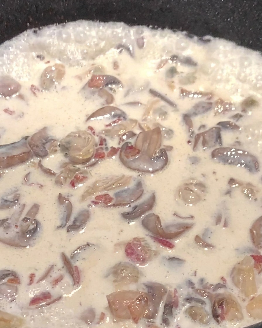 Sopa de champiñones cremosa con cubos de papa en una sartén.
