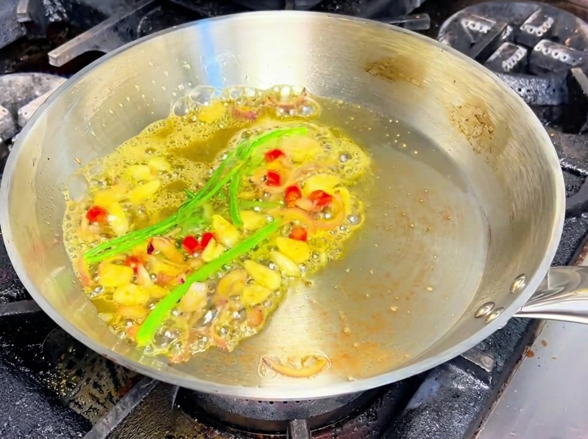 Almejas y vino blanco cocinándose a fuego lento en una sartén con ajo y chalotas.