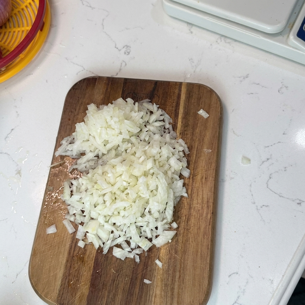 Apio, cebolla y zanahorias finamente picados sobre una tabla de madera listos para cocinar.