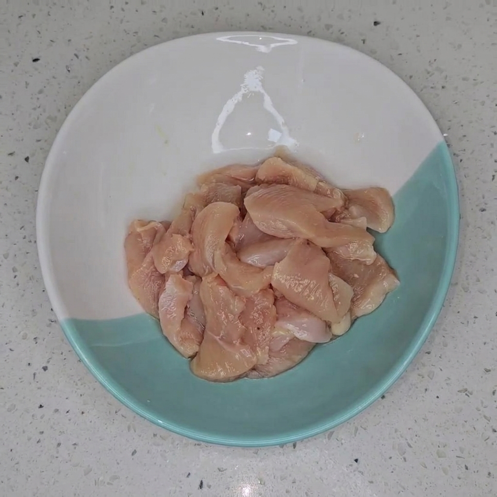 Trozos de pechuga de pollo marinando en un tazón.