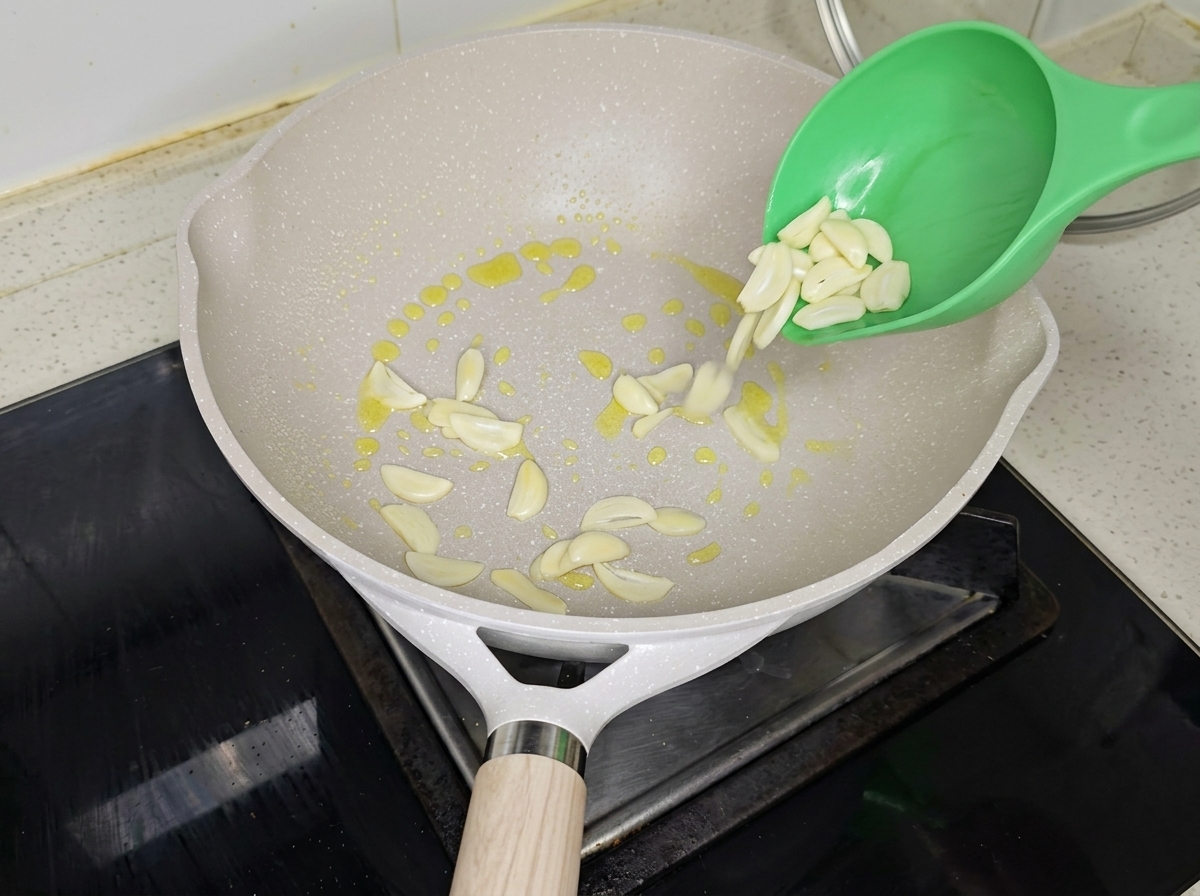 Ajo y cebollino sofriéndose en una sartén con aceite.