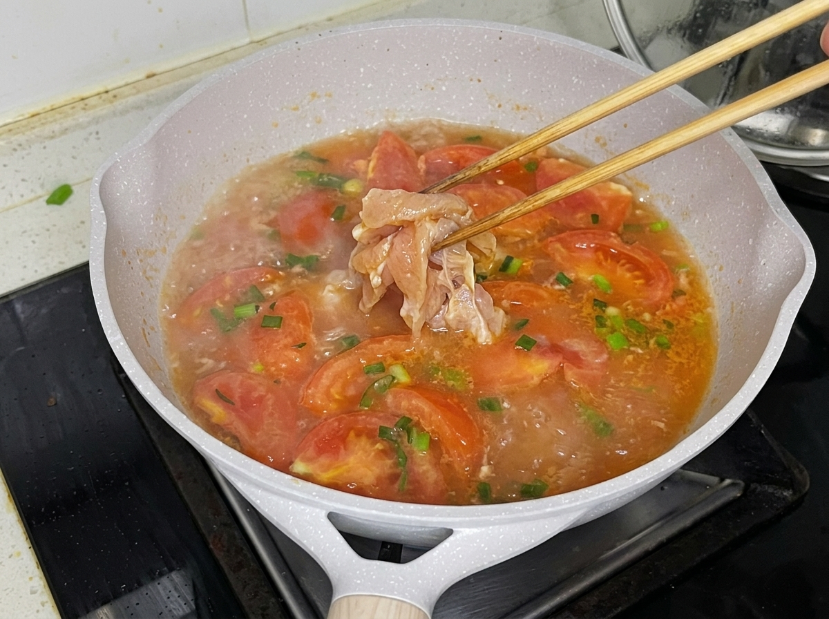 Trozos de pollo siendo añadidos cuidadosamente al caldo hirviendo.