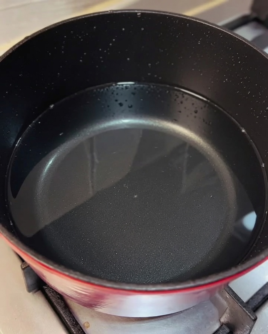 Pollo desmenuzado siendo incorporado en una olla de caldo hirviendo.