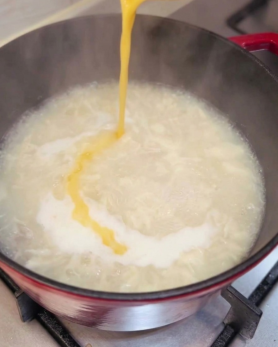 Huevo siendo vertido en la sopa, formando cintas.