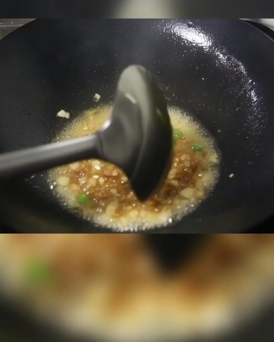Cebolletas, carne troceada y cubos de patata cocinándose en un wok caliente con aceite.