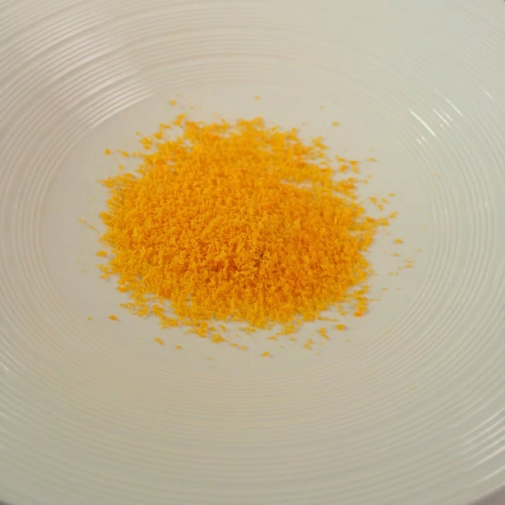 Un cuenco con una mezcla dorada de pan rallado, hierbas y queso rallado.
