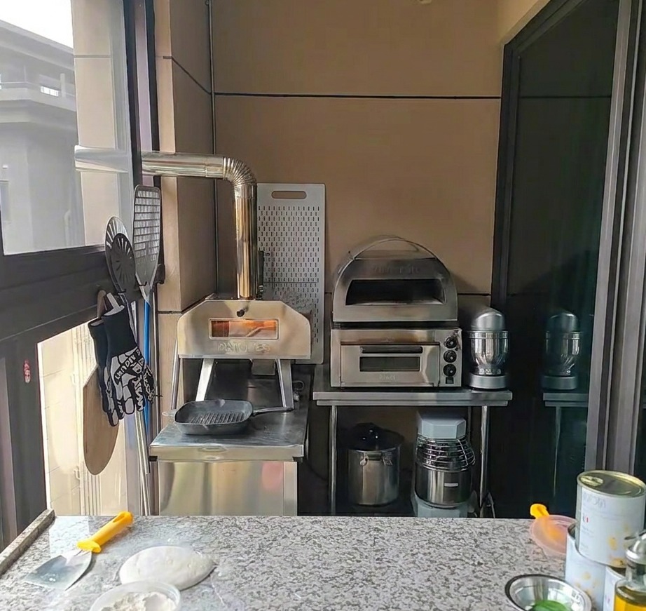 Manos estirando cuidadosamente una bola de masa de pizza fermentada sobre una encimera ligeramente enharinada.