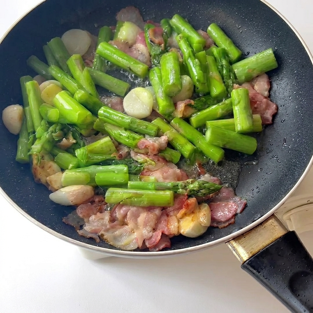 Carne picada dorándose en una olla con aceite de sésamo, removida con palillos.