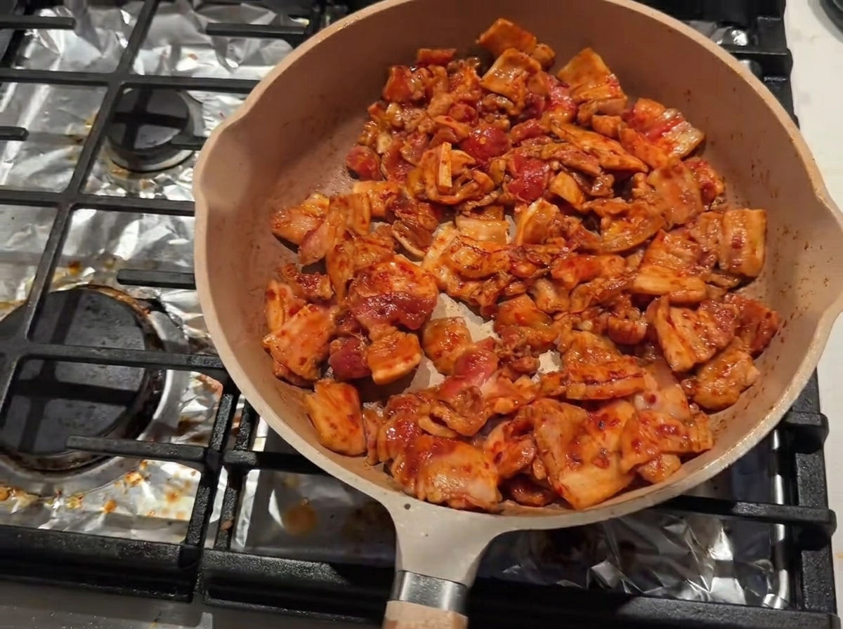 Panceta sellándose en una sartén mientras se añade vino de cocina por el borde interior.