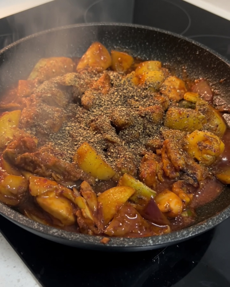 Terminando el pollo picante coreano sazonándolo con polvo de perilla en la sartén.