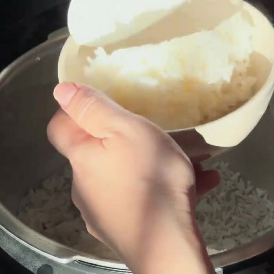 Arroz blanco al vapor sirviéndose en un bol de tono claro con una paleta para arroz.