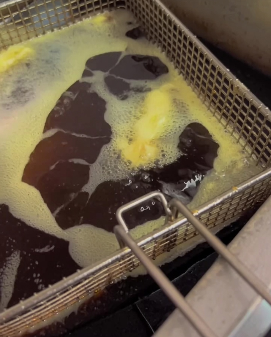 Judías verdes friéndose en aceite caliente en una freidora.