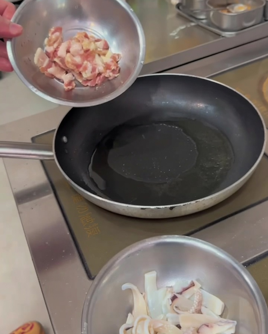 Tiras de panceta de cerdo chisporroteando en una sartén caliente, mostrando bordes dorados.