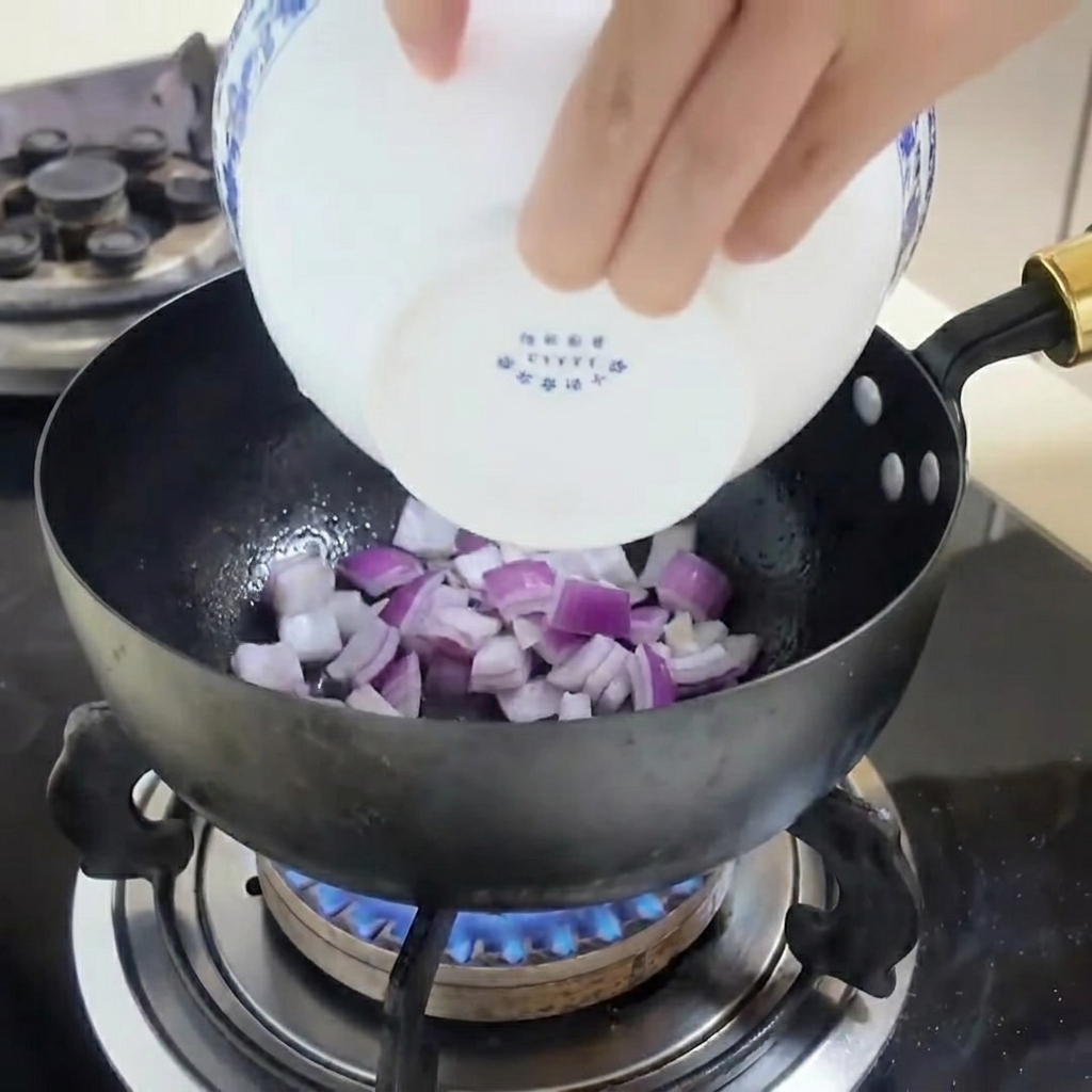 Tiras de cebolla morada salteándose en una sartén con spray de cocina.