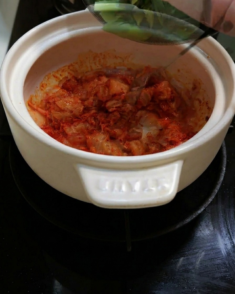 Cebollinas y cebolla roja en rodajas siendo añadidas a la olla.