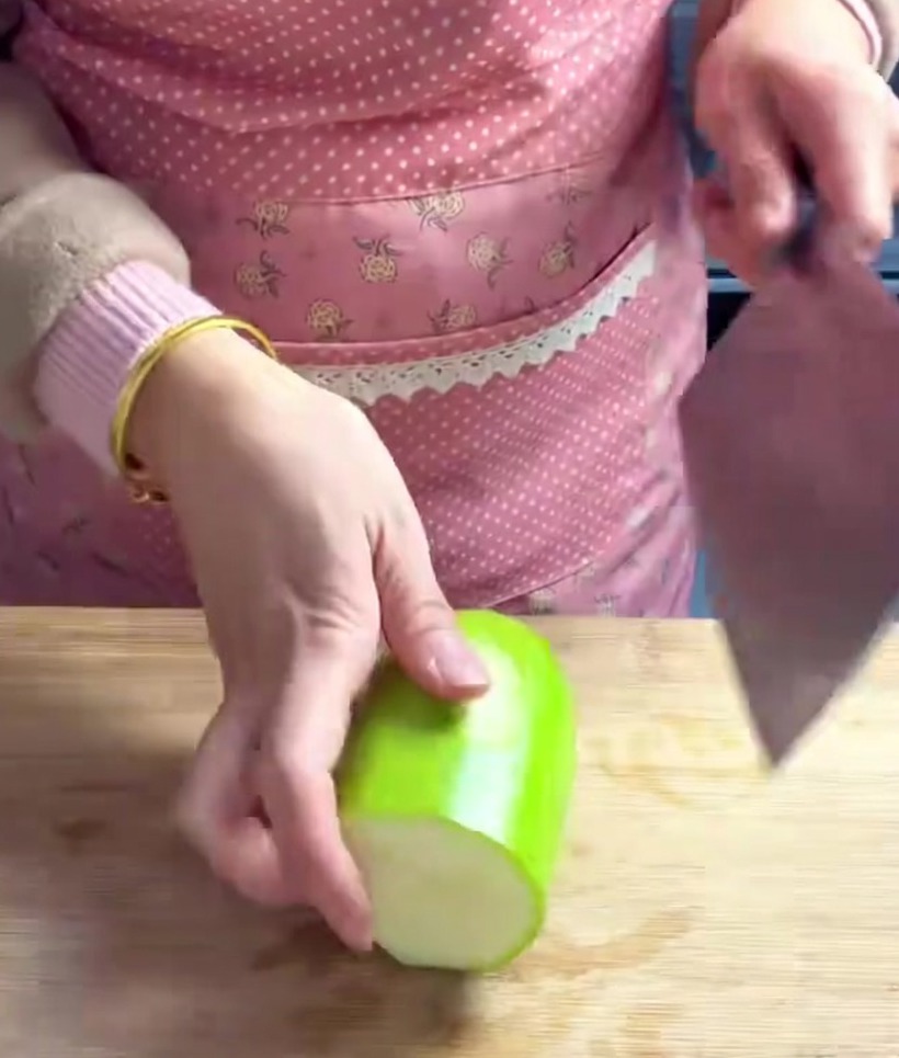 Trozos de chayote cortados en cubos uniformes y gruesos sobre una tabla de madera.