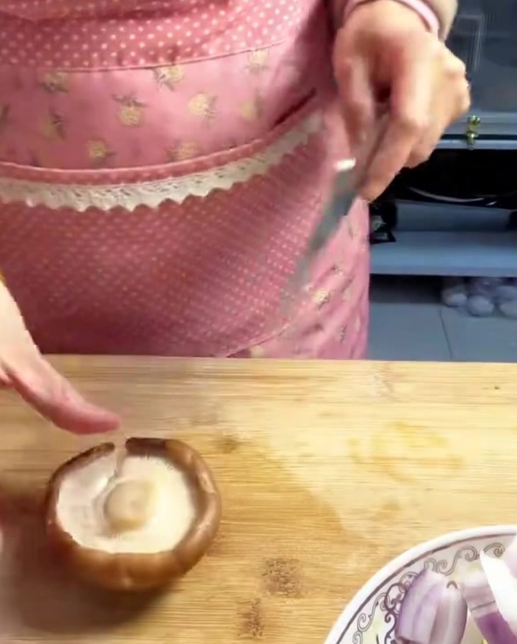 Setas shiitake frescas cortadas en tiras finas uniformes sobre una tabla de madera.
