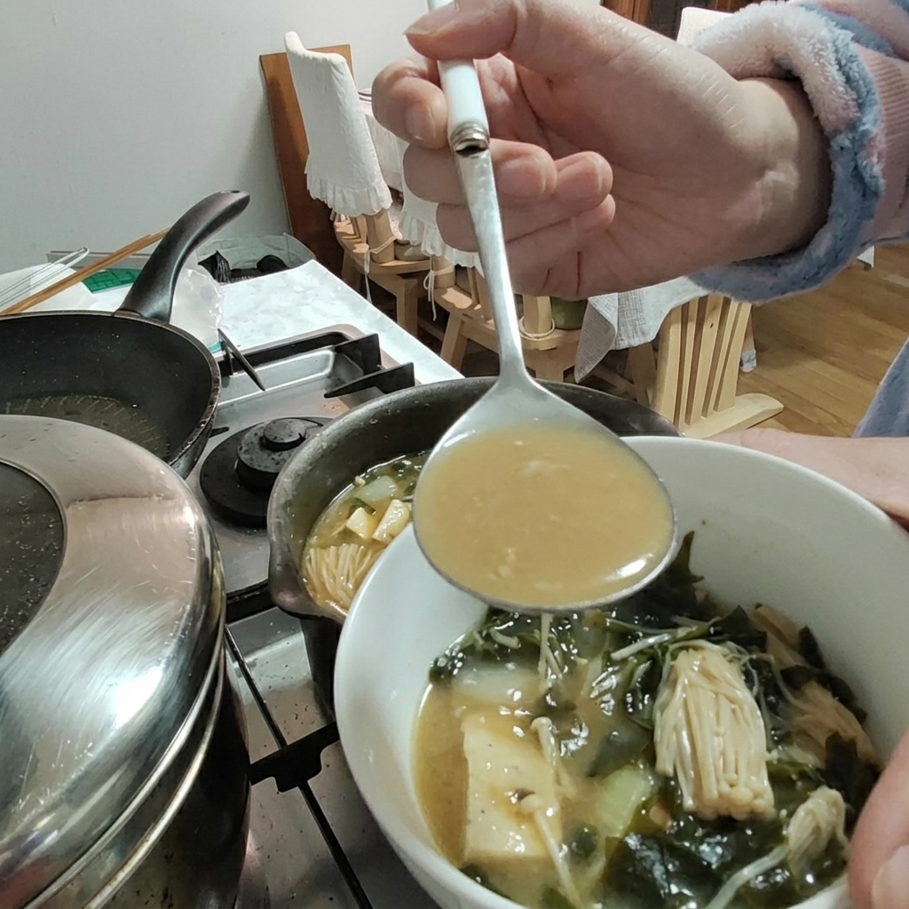 Pasta de soja siendo añadida al estofado con un cucharón.