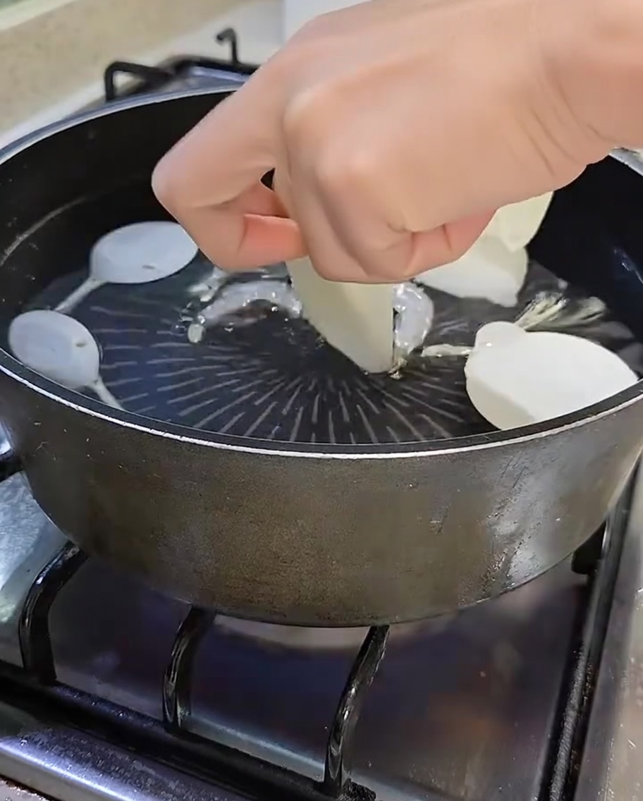 Olla con agua hirviendo, anchoas, shiitake, rábano en rodajas y cebolleta verde.