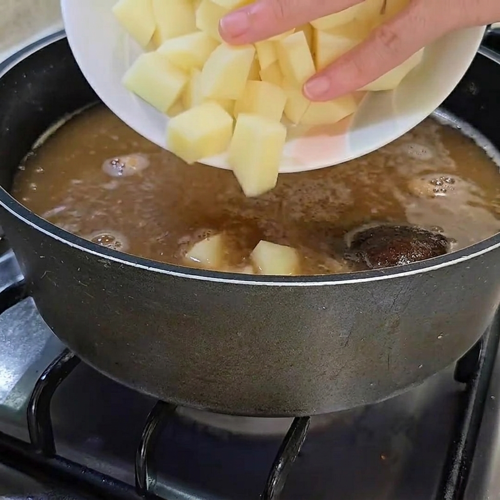 Cubos de patata cruda siendo añadidos a la olla.