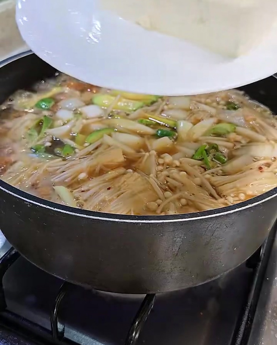 Slices of tofu being added to the stew.