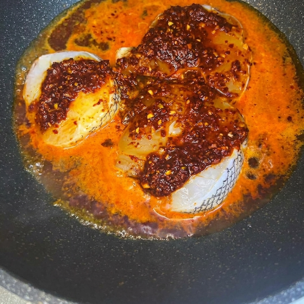 Trozos de apio verde fresco picado siendo espolvoreados sobre filetes de bacalao sazonados en una sartén.