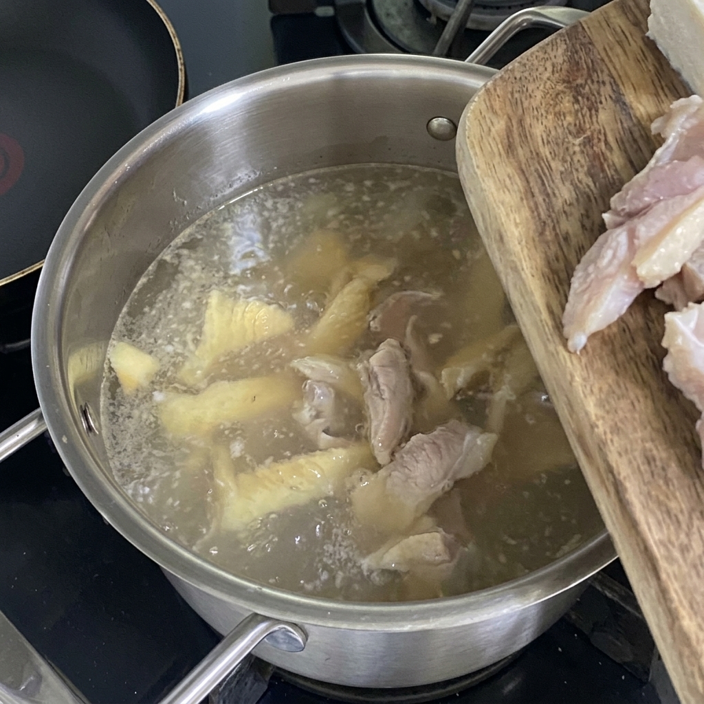 Cubos de tofu fresco siendo añadidos al caldo de abadejo claro que hierve a fuego lento.
