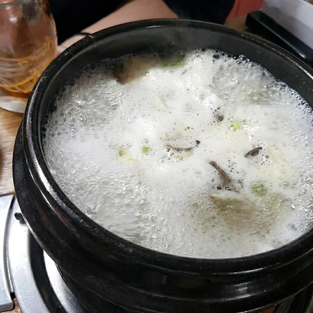 Mezclando la pasta de soja marrón en el caldo dentro de la olla de piedra.