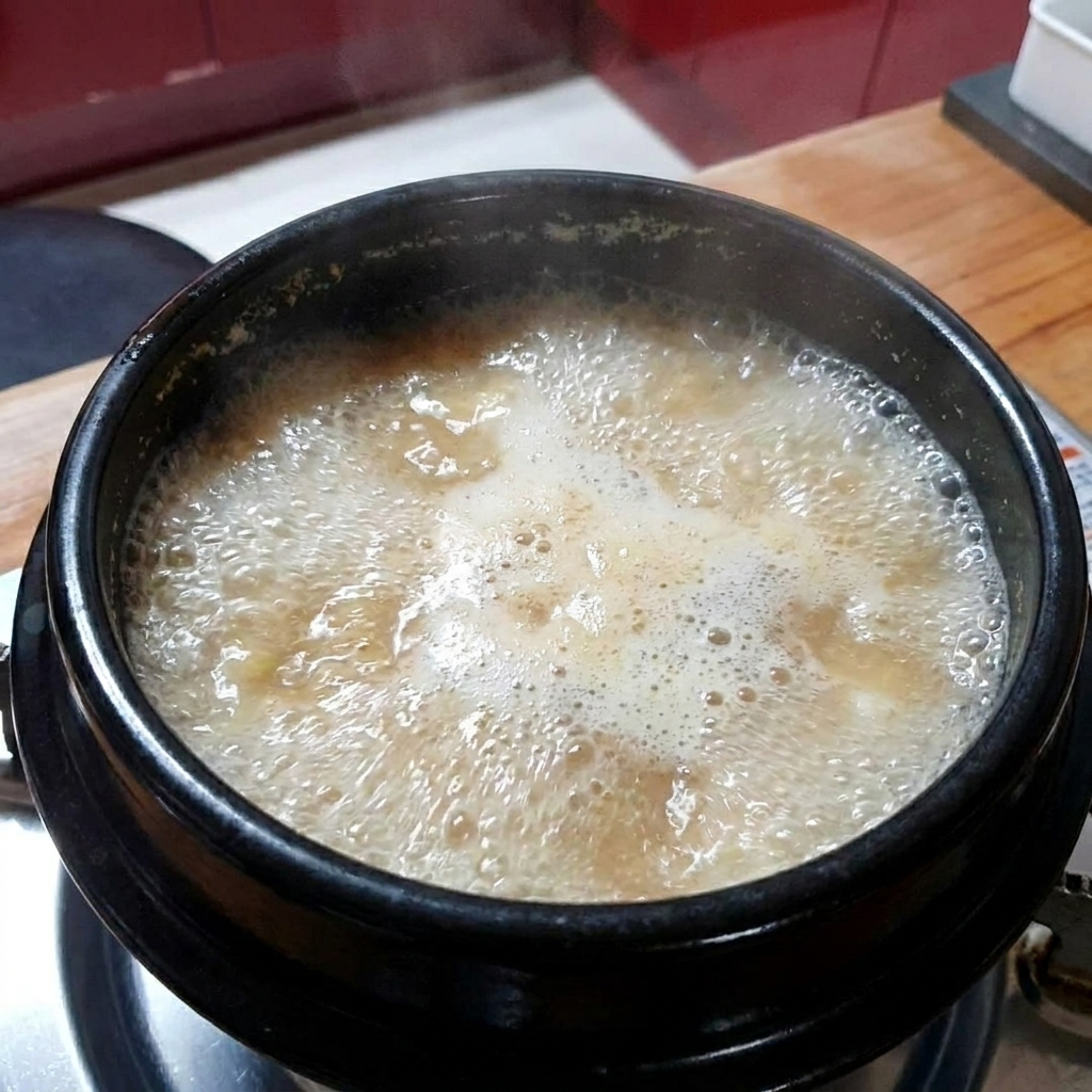 Ajo picado siendo añadido al estofado de pasta de soja hirviendo.