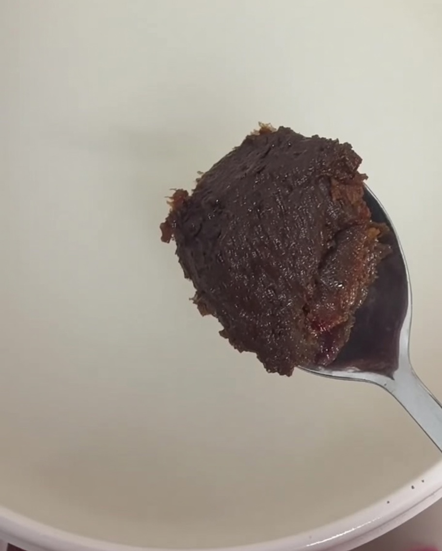 Una cuchara con pasta de soja y pasta de chile siendo disuelta en el caldo.