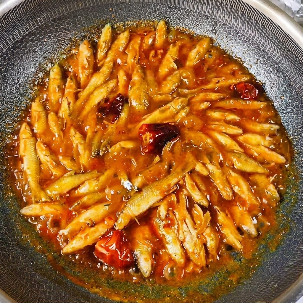 Los pescaditos de río cocinados brillando con una salsa espesa en el wok.
