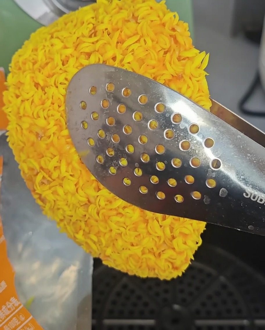 Filetes de pollo congelados colocados en la cesta de la freidora de aire con pinzas.