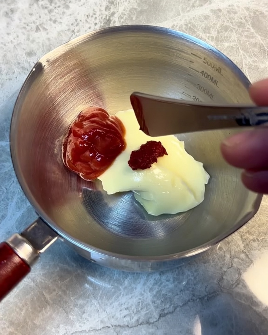 Ingredientes para la salsa de hamburguesa siendo mezclados en un recipiente de acero.