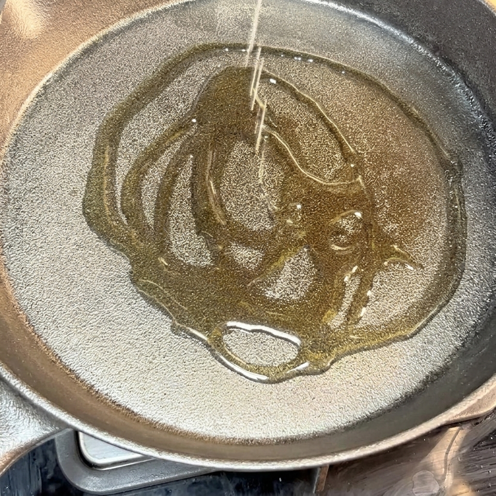Hamburguesa de ternera sazonada chisporroteando en una sartén de hierro fundido con aceite.