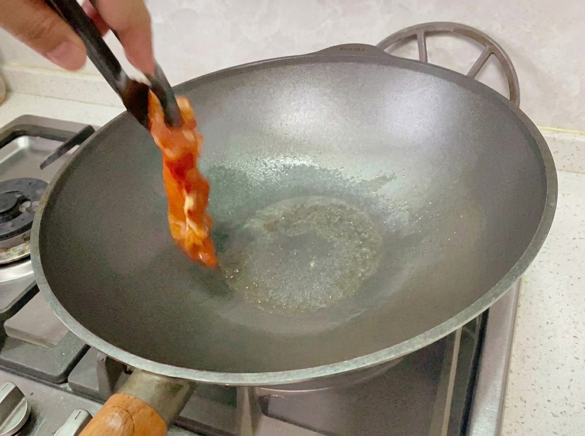 Pollo marinado cocinándose en una sartén a fuego medio-bajo.