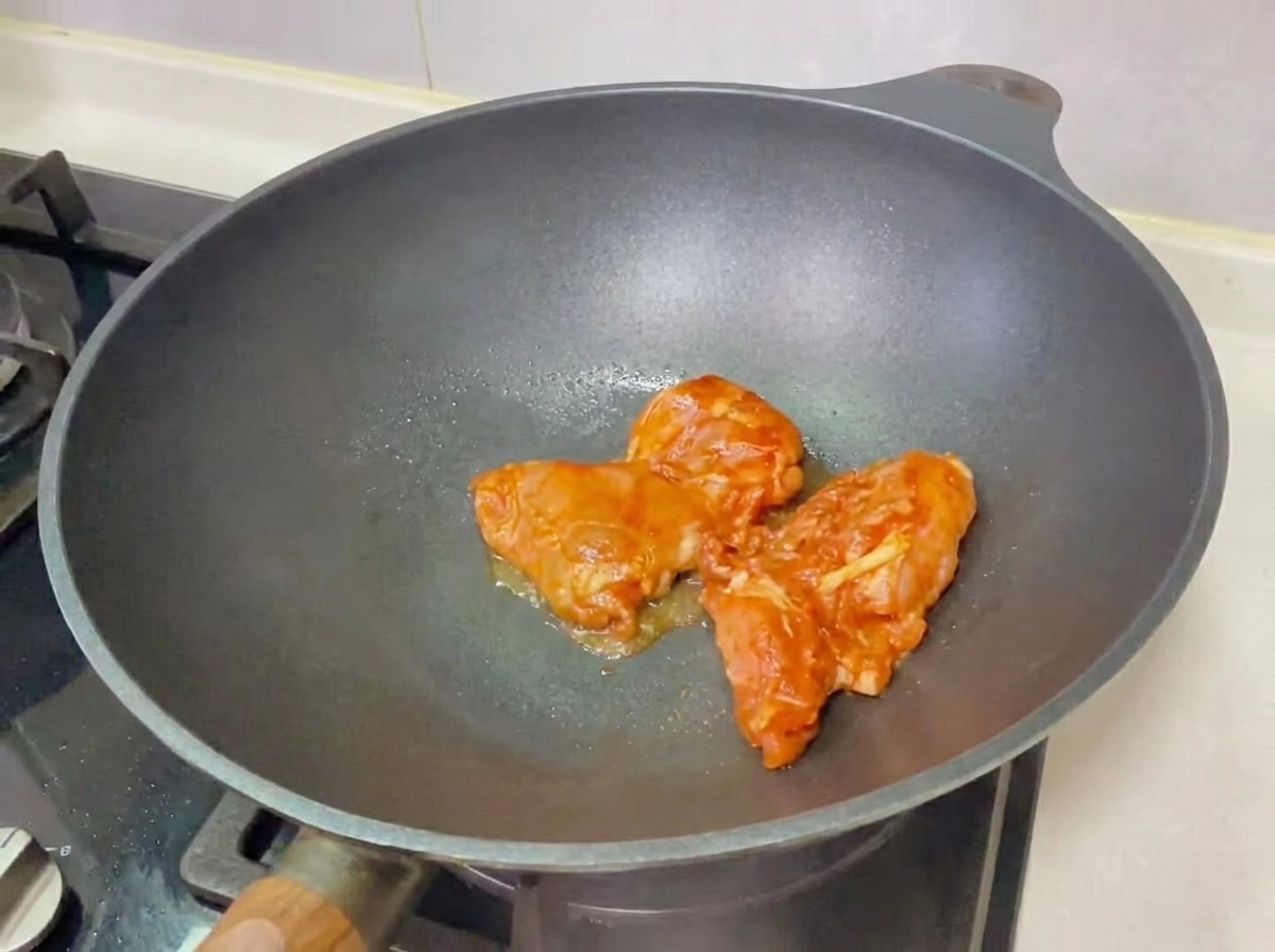 Una hamburguesa de pollo teriyaki completamente montada sobre una tabla de madera, lista para comer.