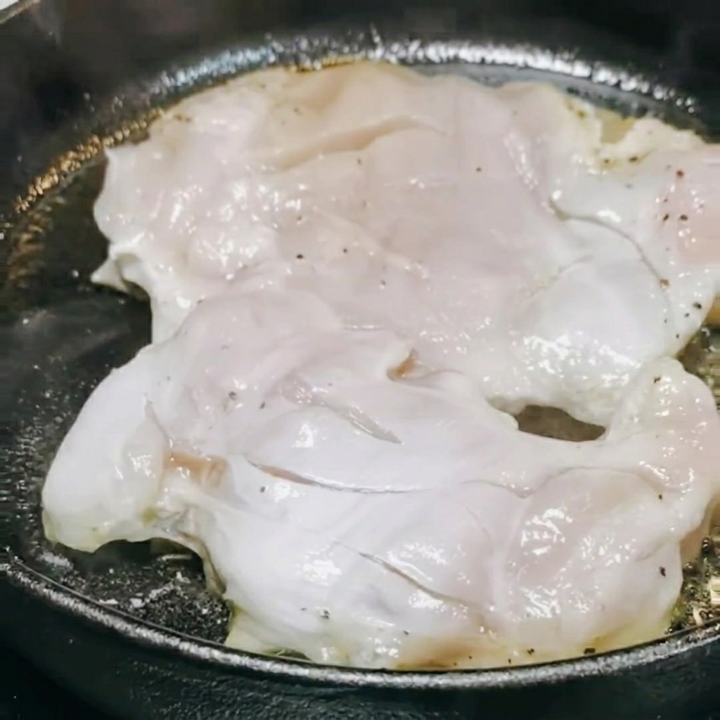 Salsa teriyaki y vino blanco siendo vertidos en la sartén sobre el pollo.
