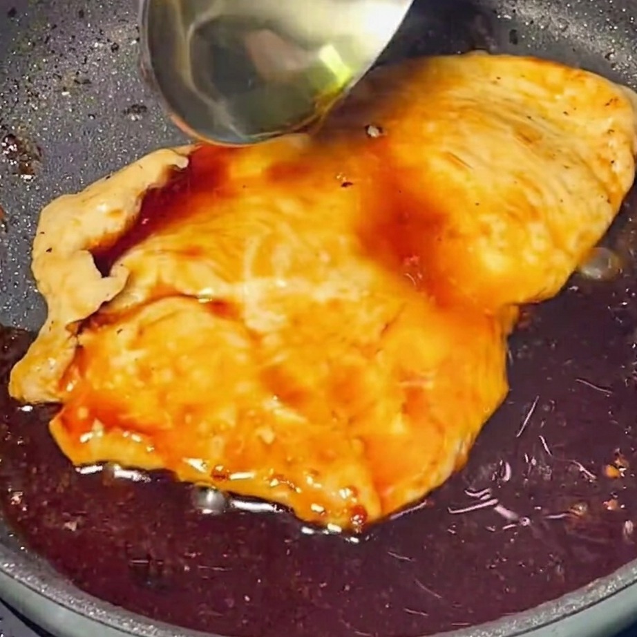 Rica y brillante salsa teriyaki vertida sobre el pollo dorado en una sartén.